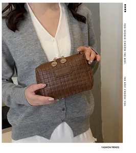 Minimalist brown woven checkered cosmetic bag held by person in stylish grey cardigan