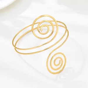 Vista detallada de un brazalete de brazo en espiral geométrica dorada con acabado pulido