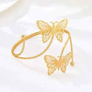 Vista detallada de un brazalete de brazo en espiral dorado con finas mariposas