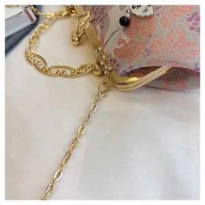 Detailed macro view of the gold butterfly clasp and chain on embroidered evening clutch