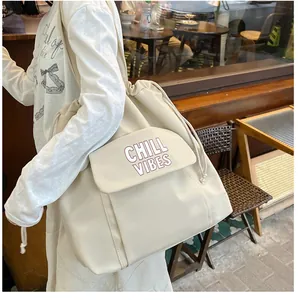 Model draagt een grote crème nylon draagtas met Chill Vibes-print in een café