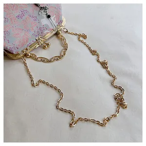 Close-up detail of golden metal chain and floral embroidery on a niche evening clutch bag
