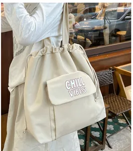 Detailweergave van een crème nylon tote tas met 'CHILL VIBES' print op de zak