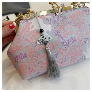 Close-up detail of luxury embroidered evening clutch with butterfly clasp and tassel