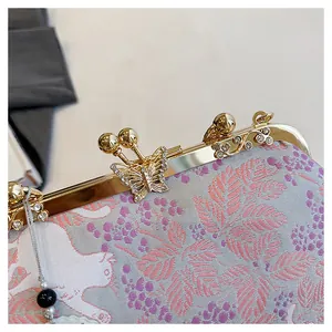 Close-up detail of crystal butterfly clasp and floral embroidery on evening clutch.