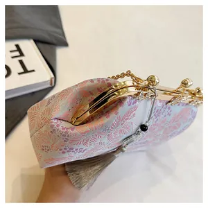 Detailed close-up showing floral embroidery and gold metal clasp on elegant evening clutch