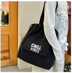 Zijaanzicht detail van een grote zwarte nylon draagtas met Chill Vibes tekst print