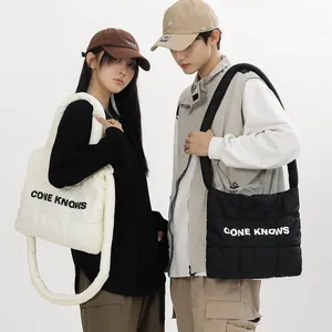 Gros plan détaillé de sacs cabas matelassés en noir et blanc portés par des mannequins.