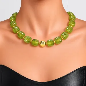 Detailed view of a green acrylic beaded necklace with a central gold accent bead.