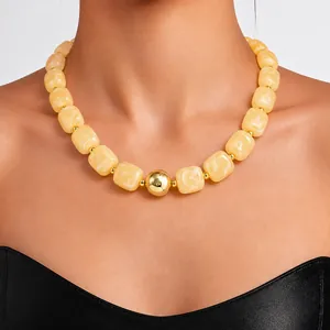 Detailed view of a chunky yellow acrylic bead necklace featuring a central gold ball accent