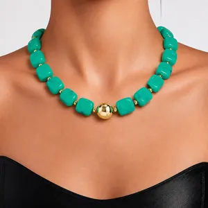 Close-up of chunky turquoise acrylic bead necklace with central gold sphere detail.