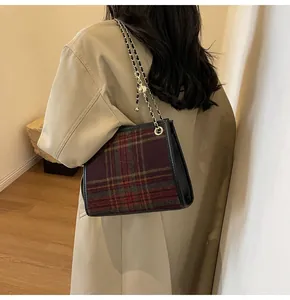 Close-up detail of a plaid woolen square shoulder bag with elegant gold chain strap