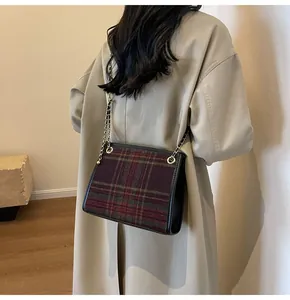 Model wearing a woolen plaid square crossbody bag with a metal chain strap.