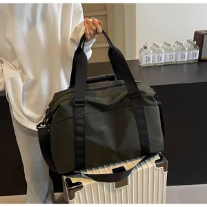 Detailed view of a dark green large capacity travel duffel bag on a white trolley suitcase