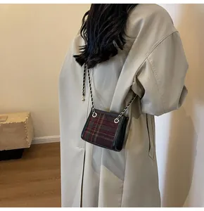 Close-up of a stylish wool plaid chain crossbody bag worn with a beige trench coat