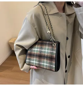 Detailed shot of a stylish plaid wool shoulder bag featuring a gold chain strap on a trench coat.
