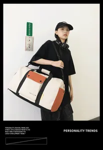 Mannequin présentant un grand sac de voyage blanc crème avec des détails orange élégants.