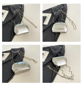 Meerdere hoeken van een zilveren avondtas met spiegeleffect en een slanke metalen ketting.
