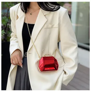 Model met een metallic rode gefacetteerde avondclutch met een gouden kettingriem