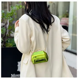 Opvallende metallic groene geometrische mini-avondtas met goudkleurige kettingriem op een model