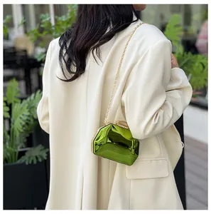 Detailweergave van een metallic groene mini clutch met gouden ketting en juwelensluiting.
