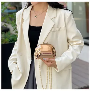 Detail van een metallic roségouden mini-avondclutch met kettingriem op een model