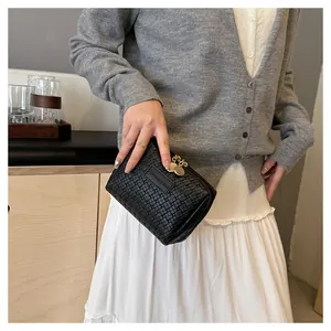 Detailed shot of a black woven checkerboard makeup pouch held by a hand in setting