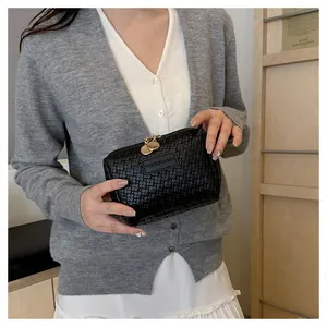 Detailed view of black checkered woven cosmetic bag held by hand, elegant pouch