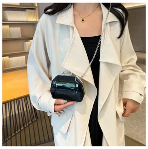 Elegante zwarte mini avondclutch met zilveren ketting en witte jas getoond.