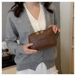 Detail showing the woven texture and golden zipper pulls of a brown cosmetic bag