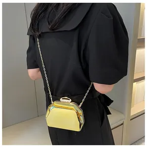 Gedetailleerd zijaanzicht van een glanzende gouden mini-avondclutch met metalen ketting
