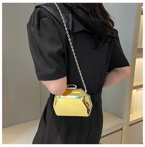 Elegante gouden metallic clutch met kettingriem, gedragen bij een stijlvolle zwarte jurk