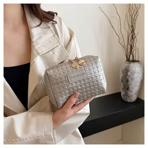 Detailed macro shot of a silver woven texture cosmetic bag with gold zippers.