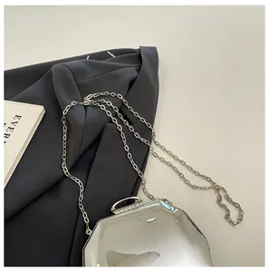 Detail van zilveren achthoekige spiegelclutch met strass-steentjes en ketting.