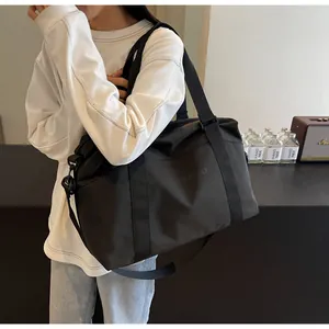 Large capacity black travel duffle bag carried by a model for a short weekend trip