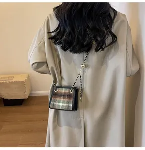 Detailed view of a trendy plaid wool crossbody bag with gold chain and adjustment ball.