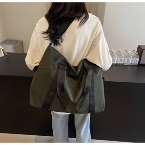 Back view of a female model carrying a large olive green travel duffle bag on her shoulder