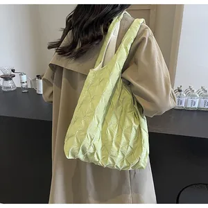 Close-up detail of a light green pleated tote bag styled with a beige trench coat.