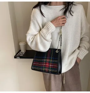 Detail view of a plaid wool crossbody bag with a stylish gold chain strap on model