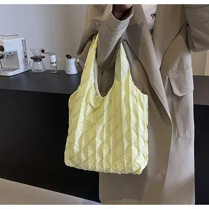 Detailed shot of a pale yellow pleated grid tote bag held by a person in a cafe