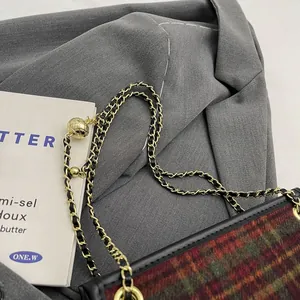 Detail view of a vintage plaid tweed crossbody bag with an elegant gold chain strap
