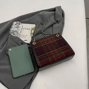 Close-up detail of fashionable plaid wool chain square bag with gold hardware on grey blazer