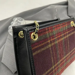 Detailed close-up of a woolen plaid small square bag featuring a gold chain and leather trim