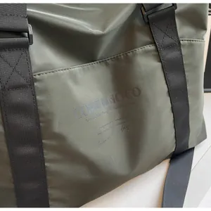 Detail view of army green travel tote with COME KNOCO print and durable nylon straps.