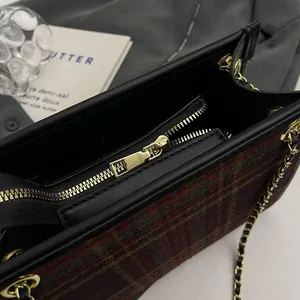 Detailed view of the interior zipper and plaid wool texture on a stylish chain tote bag.