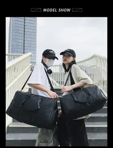 Des mannequins portant de grands sacs de voyage tressés noirs en extérieur.