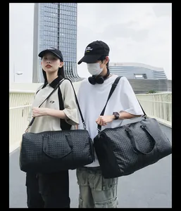 Gros plan de deux grands sacs de voyage en cuir tressé noir portés avec des tenues urbaines