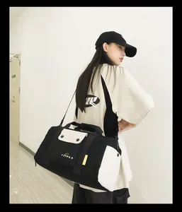 Jeune femme portant un grand sac de voyage noir et beige pour le sport et le fitness.