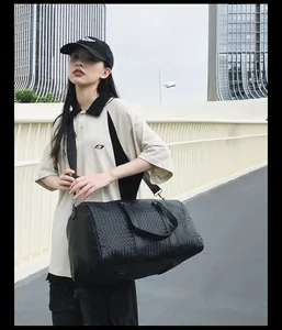 Photo lifestyle d'un sac de voyage tressé noir avec grande capacité et bandoulière.