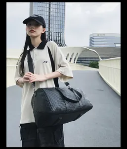Vue détaillée d'un grand sac de voyage noir tissé pour les affaires et le sport.